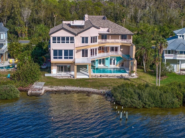 812 Point Seaside Dr, Crystal Beach, FL 34681 - back of property featuring a balcony, a water view, stucco siding, solar panels, and a wooded view