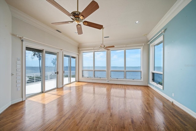 812 Point Seaside Dr, Crystal Beach, FL 34681 - empty room featuring a ceiling fan, plenty of natural light, wood finished floors, a water view, and crown molding