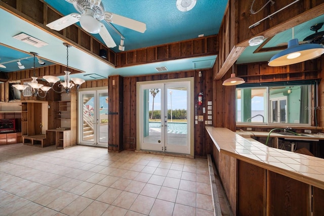 812 Point Seaside Dr, Crystal Beach, FL 34681 - kitchen with tile counters, french doors, wood walls, healthy amount of natural light, and light tile patterned floors