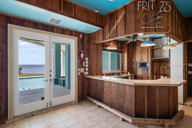 812 Point Seaside Dr, Crystal Beach, FL 34681 - kitchen with wood walls, a water view, tile countertops, french doors, and healthy amount of natural light