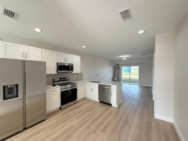 6977 Hawksbury St, Englewood, FL 34224 - kitchen with stainless steel appliances, a sink, a peninsula, light countertops, and white cabinets