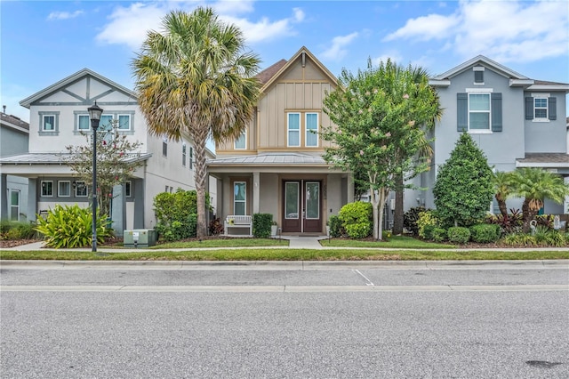 7238 Milestone Dr, Apollo Beach, FL 33572 - view of front of house with a standing seam roof, metal roof, stucco siding, covered porch, and french doors