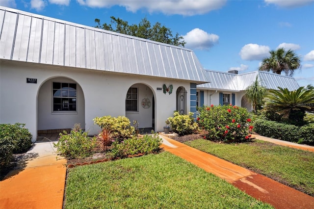 4229 Glissade Dr, New Port Richey, FL 34652 - view of front of house featuring metal roof, stucco siding, and a front lawn