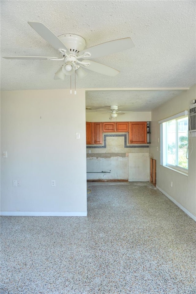 14501 N Bayshore Dr, Madeira Beach, FL 33708 - unfurnished living room featuring a textured ceiling, baseboards, and ceiling fan