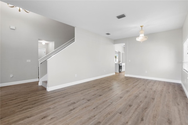 4852 Trinidad Dr, Land O Lakes, FL 34639 - unfurnished living room featuring a chandelier, wood finished floors, stairway, and baseboards