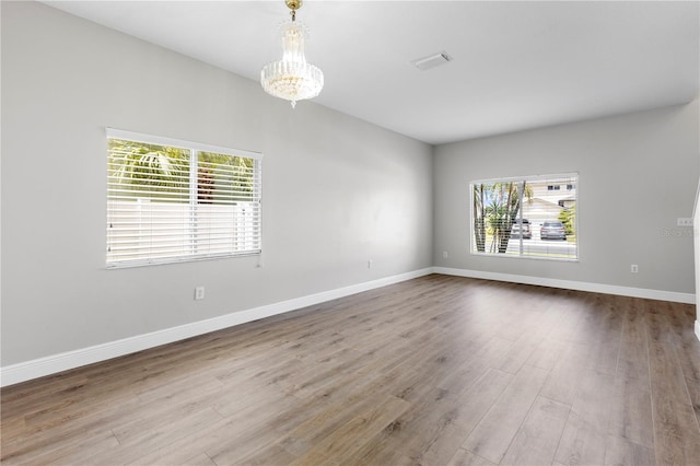 4852 Trinidad Dr, Land O Lakes, FL 34639 - unfurnished room featuring healthy amount of natural light, a chandelier, wood finished floors, and baseboards