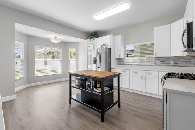 4852 Trinidad Dr, Land O Lakes, FL 34639 - kitchen with stainless steel fridge, black microwave, decorative backsplash, wood finished floors, and white cabinetry