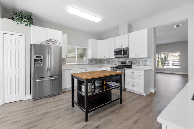 4852 Trinidad Dr, Land O Lakes, FL 34639 - kitchen featuring appliances with stainless steel finishes, light countertops, backsplash, and white cabinets