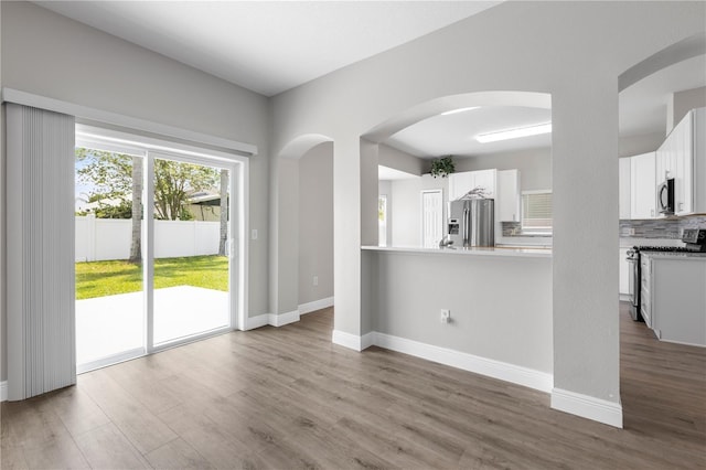 4852 Trinidad Dr, Land O Lakes, FL 34639 - kitchen with appliances with stainless steel finishes, wood finished floors, white cabinetry, and arched walkways