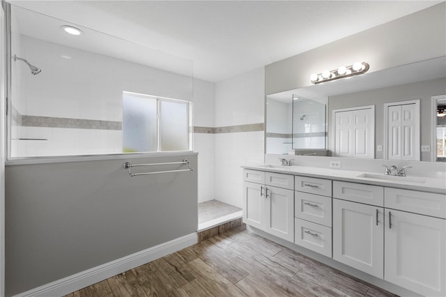4852 Trinidad Dr, Land O Lakes, FL 34639 - bathroom with a walk in shower, double vanity, wood finished floors, and baseboards
