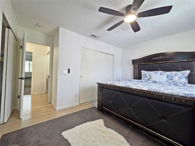 12701 N 57th St -, Unit Tampa, FL 33617 - carpeted bedroom with a textured ceiling, wood finished floors, a closet, a ceiling fan, and baseboards
