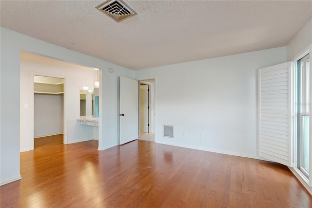 2138 Viola Dr, Clearwater, FL 33764 - unfurnished bedroom with wood finished floors, a spacious closet, baseboards, a textured ceiling, and a closet