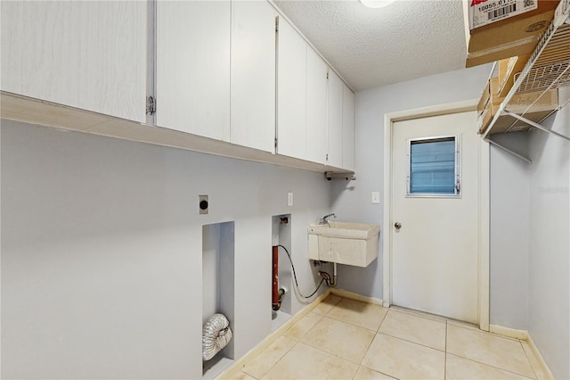 2138 Viola Dr, Clearwater, FL 33764 - washroom featuring cabinet space, electric dryer hookup, light tile patterned floors, baseboards, and a textured ceiling