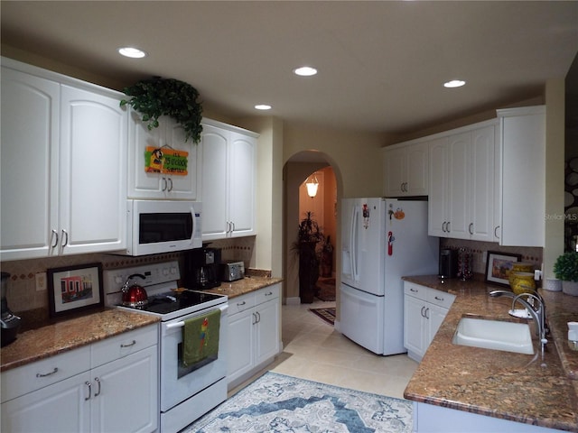 13860 Avon Park Cir Unit 104, Fort Myers, FL 33912 - kitchen with white appliances, a sink, arched walkways, white cabinets, and decorative backsplash
