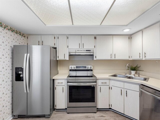 10356 Carrollwood Ln Unit 204, Tampa, FL 33618 - kitchen featuring stainless steel appliances, under cabinet range hood, a sink, wallpapered walls, and light countertops