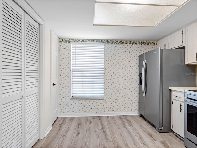 10356 Carrollwood Ln Unit 204, Tampa, FL 33618 - kitchen with wallpapered walls, light wood finished floors, stainless steel appliances, light countertops, and baseboards