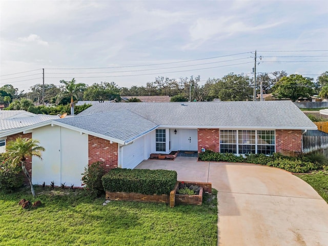 14341 Passage Way, Seminole, FL 33776 - single story home with brick siding, a shingled roof, an attached garage, and driveway