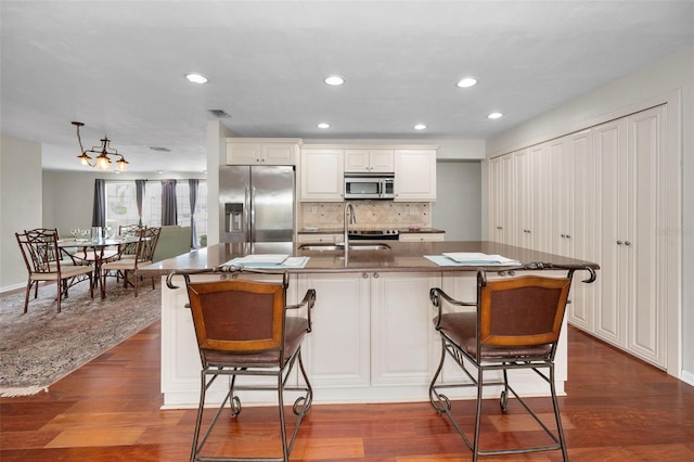 14341 Passage Way, Seminole, FL 33776 - kitchen featuring appliances with stainless steel finishes, a sink, backsplash, recessed lighting, and a breakfast bar area