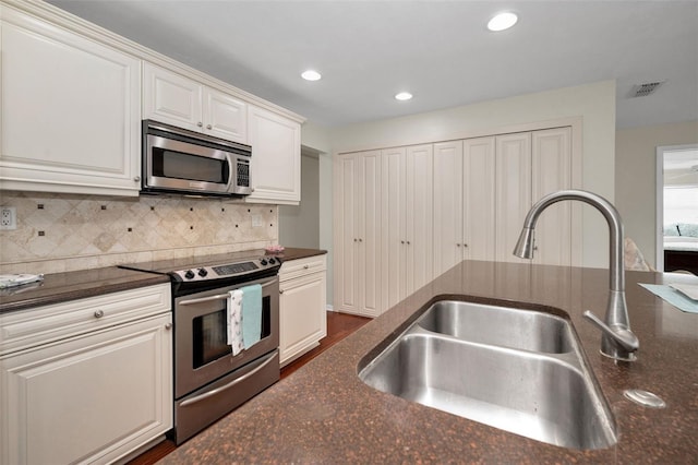 14341 Passage Way, Seminole, FL 33776 - kitchen with appliances with stainless steel finishes, a sink, backsplash, white cabinets, and dark stone countertops