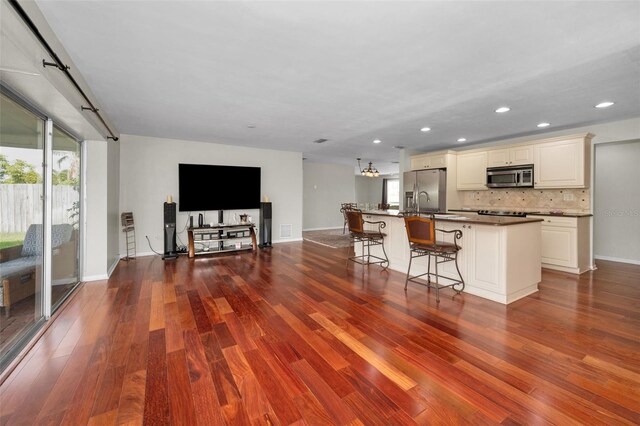 14341 Passage Way, Seminole, FL 33776 - kitchen with appliances with stainless steel finishes, dark wood finished floors, open floor plan, a kitchen breakfast bar, and a center island with sink