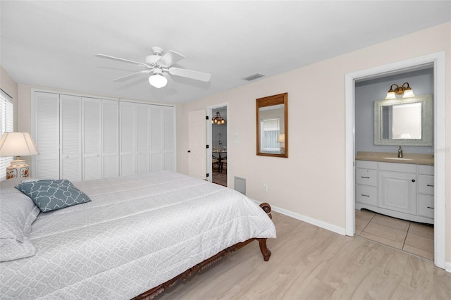 14341 Passage Way, Seminole, FL 33776 - bedroom featuring a sink, light wood finished floors, baseboards, ceiling fan, and ensuite bathroom