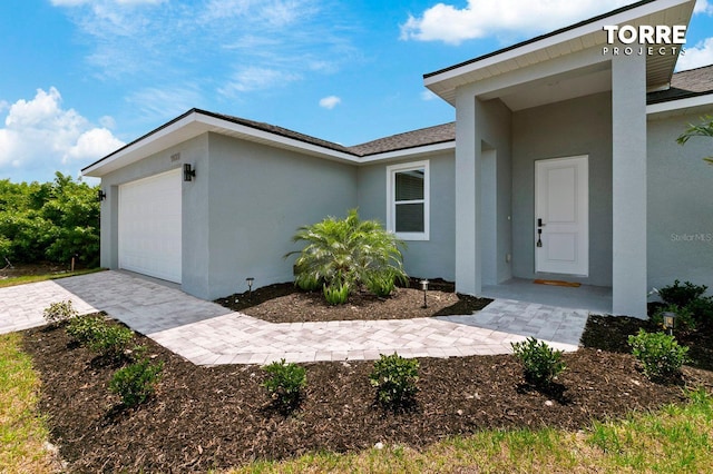 14024 Wenzel Ave, Port Charlotte, FL 33981 - doorway to property with stucco siding, a garage, and decorative driveway