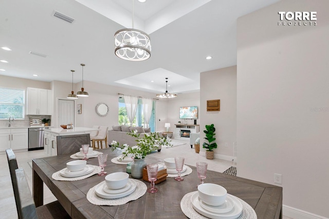 14024 Wenzel Ave, Port Charlotte, FL 33981 - dining room with a chandelier, a raised ceiling, recessed lighting, baseboards, and a warm lit fireplace