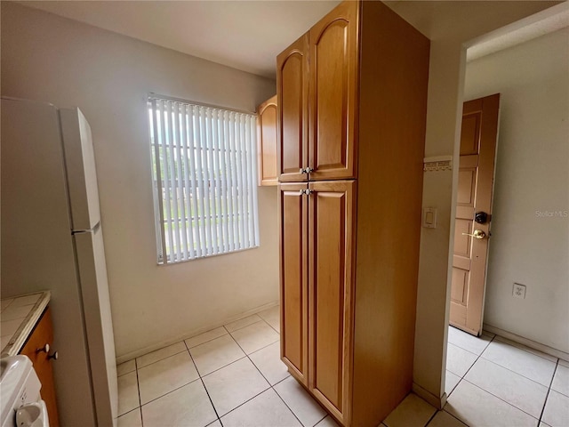 1510 Mission Hills Blvd Unit 19-F, Clearwater, FL 33759 - kitchen with light tile patterned floors, freestanding refrigerator, and brown cabinets