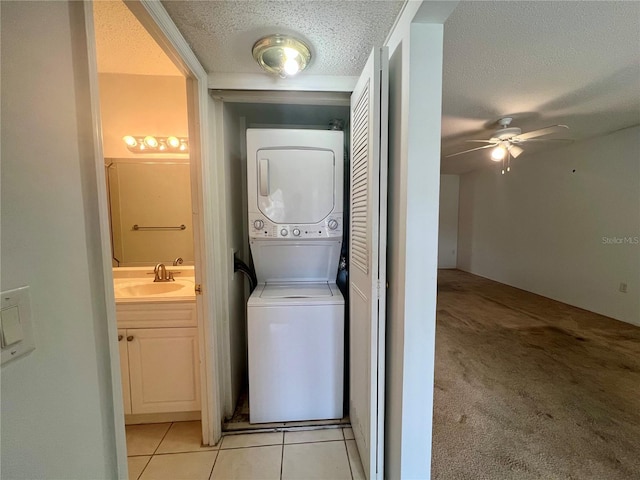 1510 Mission Hills Blvd Unit 19-F, Clearwater, FL 33759 - laundry area featuring stacked washer and clothes dryer, a textured ceiling, a ceiling fan, light tile patterned floors, and light colored carpet