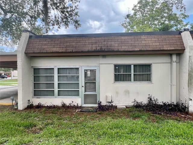 1510 Mission Hills Blvd Unit 19-F, Clearwater, FL 33759 - view of front of property featuring a shingled roof, a front lawn, and a carport