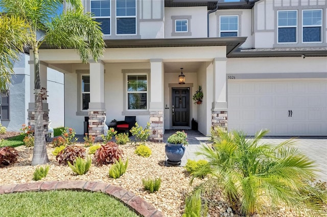 5026 Bromeliad Ave, Wimauma, FL 33598 - view of exterior entry featuring stucco siding, an attached garage, stone siding, and a porch
