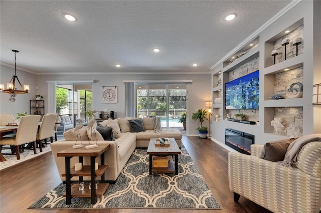 5026 Bromeliad Ave, Wimauma, FL 33598 - living room featuring built in shelves, a textured ceiling, a glass covered fireplace, crown molding, and wood finished floors