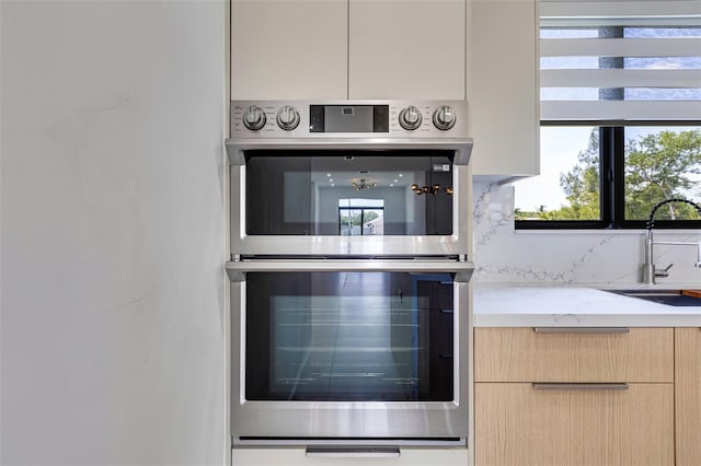 3578 NE 9th Pl, Cape Coral, FL 33909 - kitchen with double oven, a sink, modern cabinets, tasteful backsplash, and light stone counters