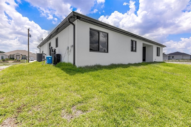 3578 NE 9th Pl, Cape Coral, FL 33909 - view of side of property with stucco siding, a lawn, and central AC unit