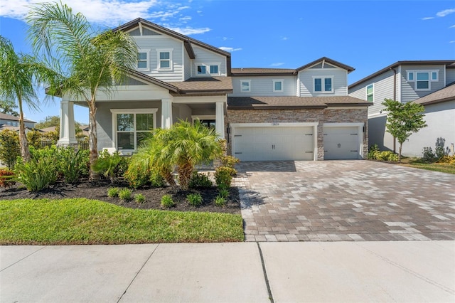 13859 Sharp Hawk Dr, Riverview, FL 33569 - view of front of home with decorative driveway, an attached garage, stone siding, roof with shingles, and a porch
