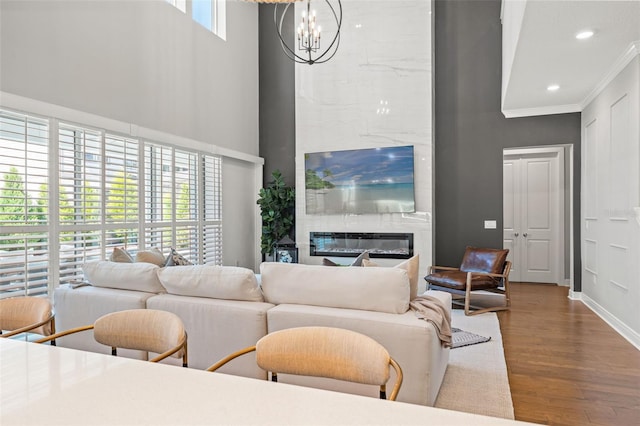 13859 Sharp Hawk Dr, Riverview, FL 33569 - living room featuring a high ceiling, crown molding, a chandelier, a premium fireplace, and wood finished floors