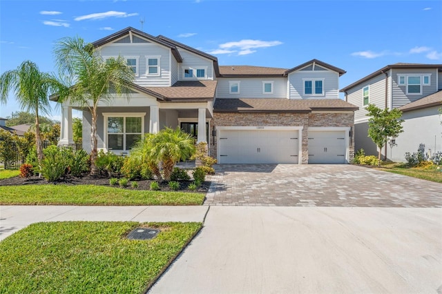 13859 Sharp Hawk Dr, Riverview, FL 33569 - view of front facade with driveway, an attached garage, stone siding, and roof with shingles