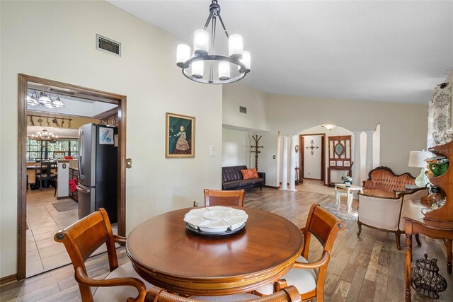 11109 Winn Rd, Riverview, FL 33569 - dining room featuring a chandelier, arched walkways, light wood-style flooring, and high vaulted ceiling