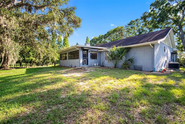 11109 Winn Rd, Riverview, FL 33569 - rear view of house with stucco siding, a yard, central AC unit, and a chimney