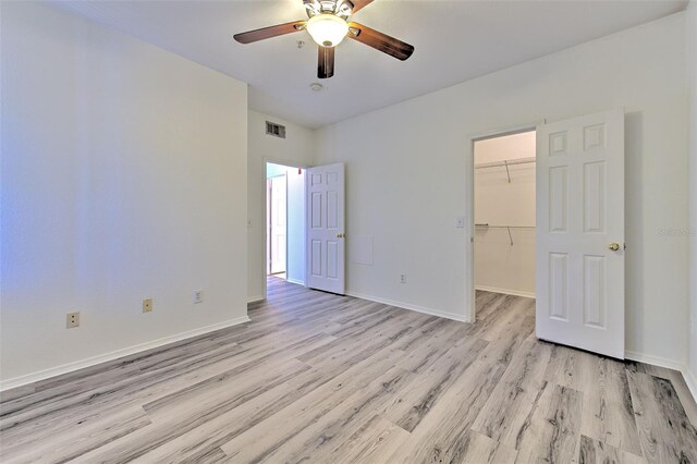 13025 Sanctuary Cove Dr Unit 301, Temple Terrace, FL 33637 - unfurnished bedroom featuring light wood-style flooring, a walk in closet, a closet, baseboards, and a ceiling fan
