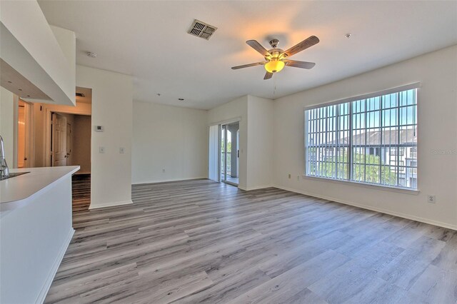 13025 Sanctuary Cove Dr Unit 301, Temple Terrace, FL 33637 - unfurnished living room featuring light wood-style flooring, a ceiling fan, baseboards, and a sink