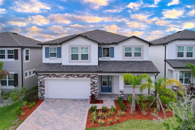 3063 Marine Grass Dr, Wimauma, FL 33598 - view of front of home featuring stucco siding, decorative driveway, roof with shingles, a garage, and stone siding
