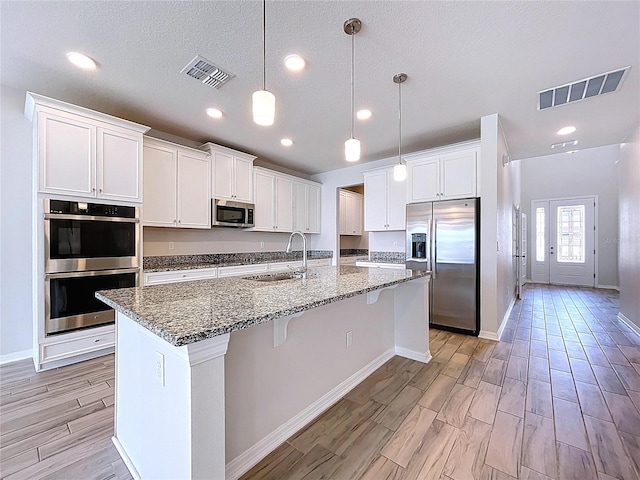 3063 Marine Grass Dr, Wimauma, FL 33598 - kitchen with appliances with stainless steel finishes, a sink, white cabinets, wood tiled floors, and stone counters