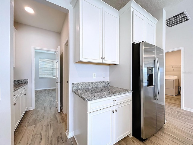 3063 Marine Grass Dr, Wimauma, FL 33598 - kitchen with stainless steel refrigerator with ice dispenser, white cabinetry, light stone counters, light wood-style flooring, and baseboards