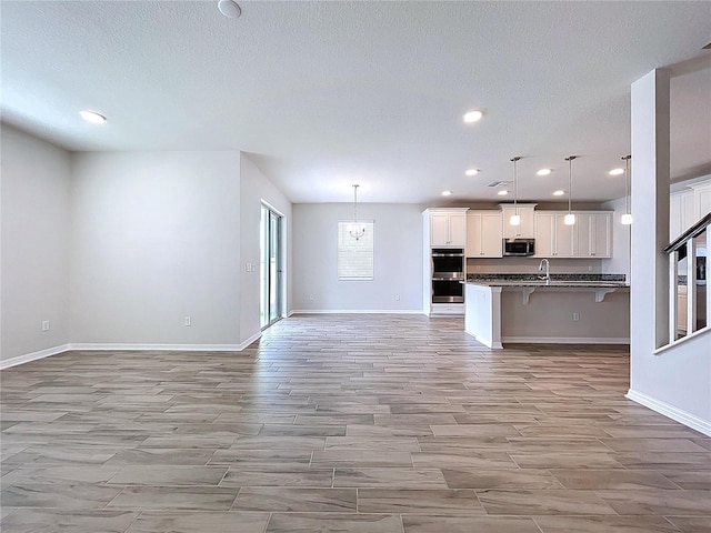 3063 Marine Grass Dr, Wimauma, FL 33598 - kitchen with appliances with stainless steel finishes, open floor plan, a breakfast bar area, dark countertops, and light wood-type flooring