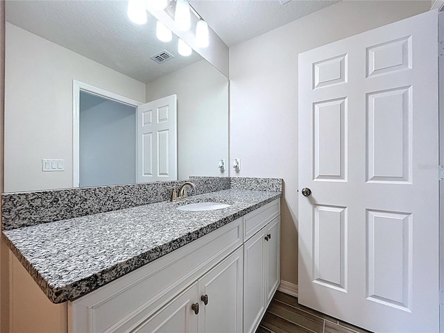 3063 Marine Grass Dr, Wimauma, FL 33598 - bathroom with vanity, wood finished floors, a textured ceiling, and baseboards