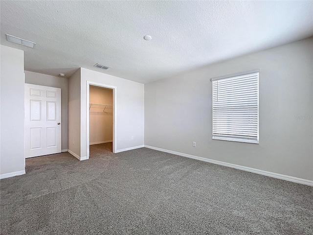 3063 Marine Grass Dr, Wimauma, FL 33598 - unfurnished bedroom featuring dark carpet, a textured ceiling, a spacious closet, baseboards, and a closet