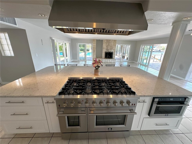 3654 Corsair Ct, New Port Richey, FL 34652 - kitchen featuring double oven range, wall chimney exhaust hood, open floor plan, light stone countertops, and plenty of natural light