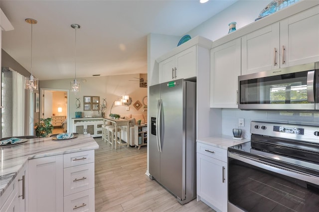 214 Lookout Dr, Apollo Beach, FL 33572 - kitchen featuring appliances with stainless steel finishes, white cabinetry, light wood-style floors, light stone countertops, and pendant lighting