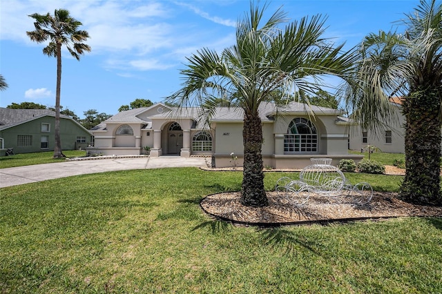 14181 Cornewall Ln, Spring Hill, FL 34609 - mediterranean / spanish house featuring stucco siding, curved driveway, and a front yard